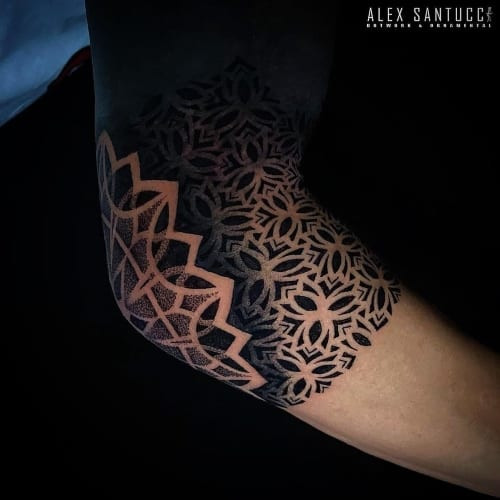 An elbow web tattoo with geometric design on a man's elbow, unique placement