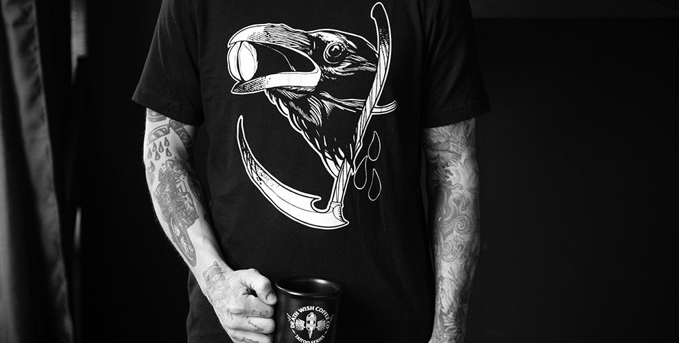 Close-up of the Death Wish Coffee 'Raven and Reaper' t-shirt designed by tattoo artist Emmanuel Mendoza. A striking coffee tattoo design now available as merch.