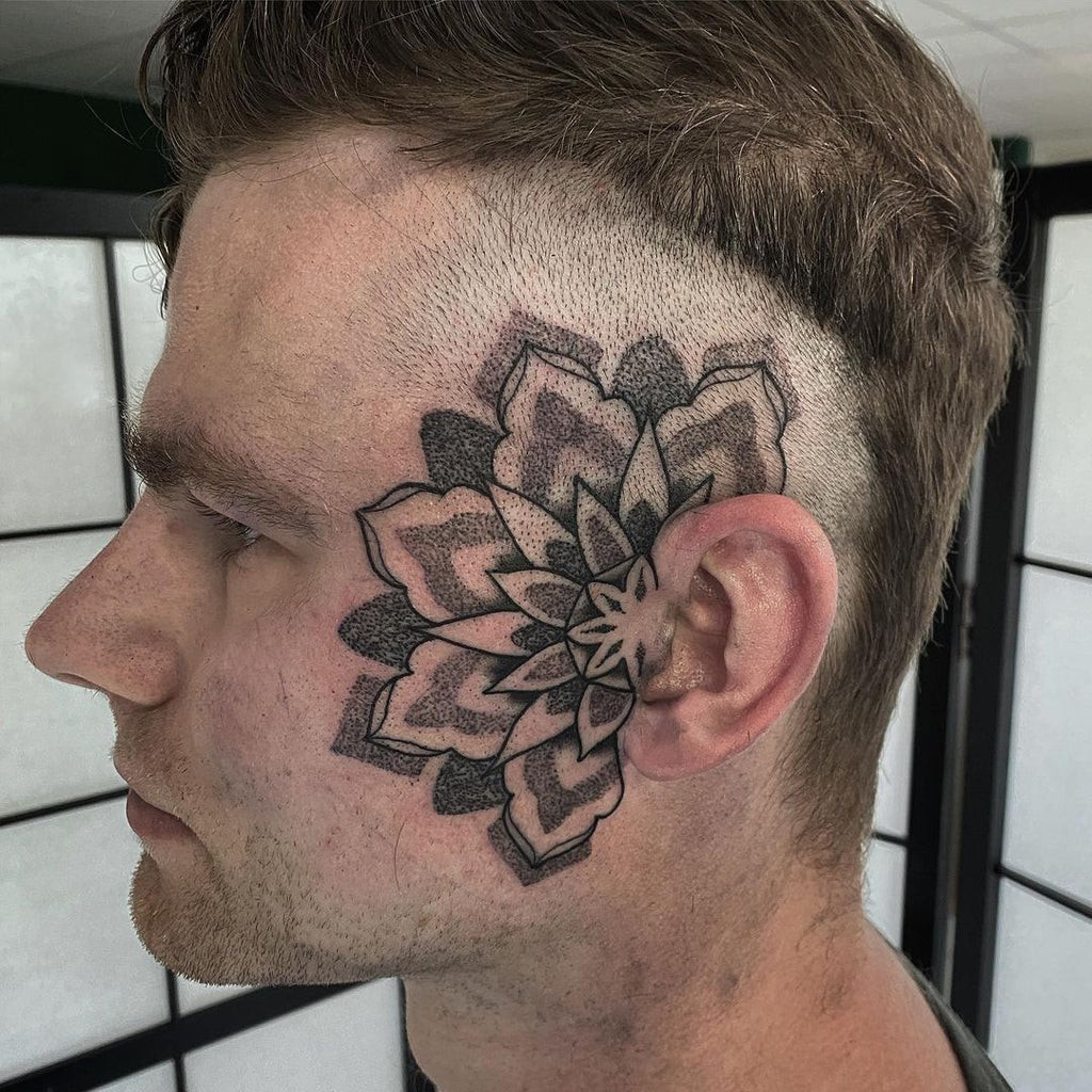 Detailed blackwork face tattoo of floral and ornamental elements, creating a striking and elegant facial adornment.