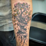 Detailed family tree tattoo on a man's arm, showcasing branches with names, a popular family tattoo idea for men.