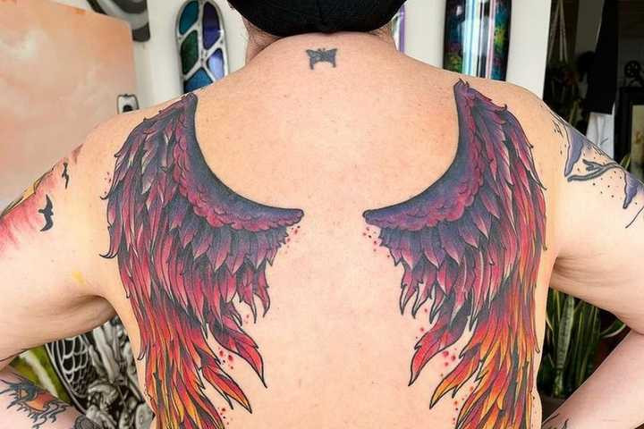 Elegant phoenix wing tattoos spanning a woman's back, detailed with fiery feather designs to symbolize freedom, transformation, and the empowering spirit of the mythical bird.