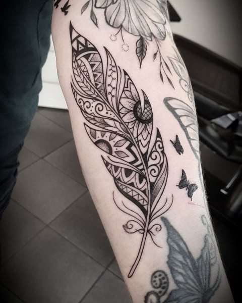 Detailed feather and bird tattoo on the arm, combining symbols of freedom and nature in men tattoo ideas.