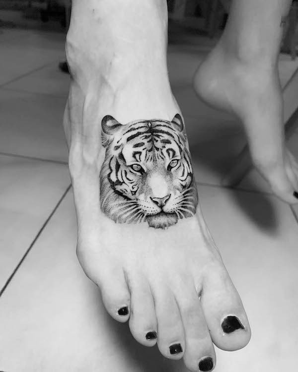 Fierce tiger foot tattoo for women, a hyper-detailed and sleek design representing strength and feminine power