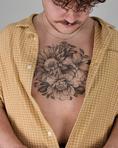 Man with a floral chest tattoo featuring detailed flowers and leaves