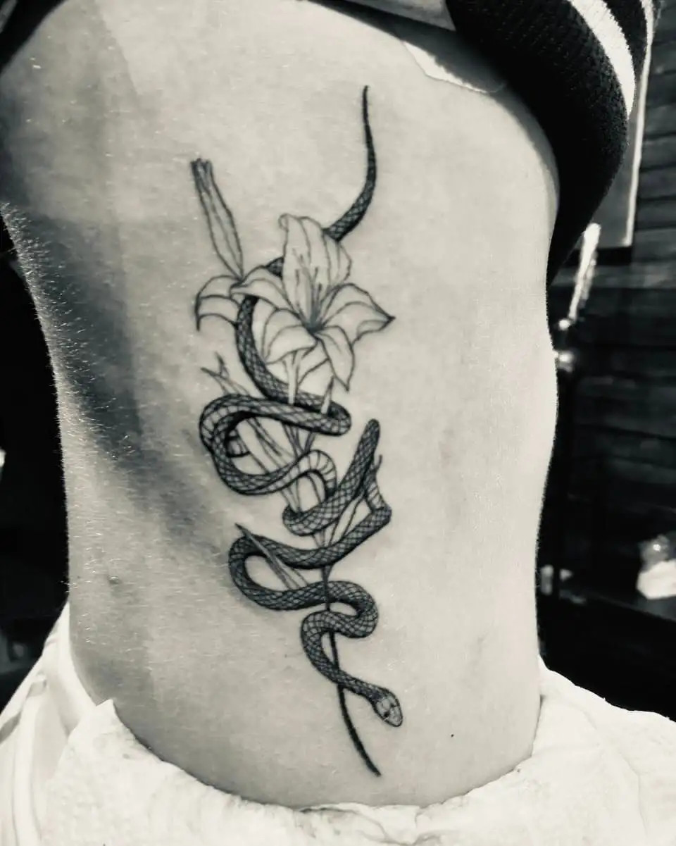 Intriguing combination of flowers and snake tattoo on a woman's side