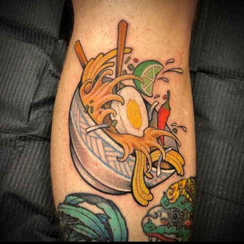 Two food tattoos on men, one on the forearm with a realistic burger and fries and another on the arm with a minimalist food icon.