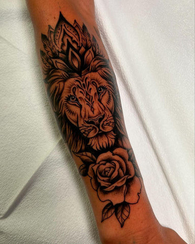 Forearm tattoo combining a majestic lion's head with a delicate rose, symbolizing strength, leadership, and the balance of power and beauty.