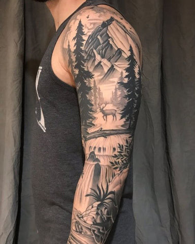 Forest sleeve tattoo featuring trees, mountains, and wildlife in a naturalistic style