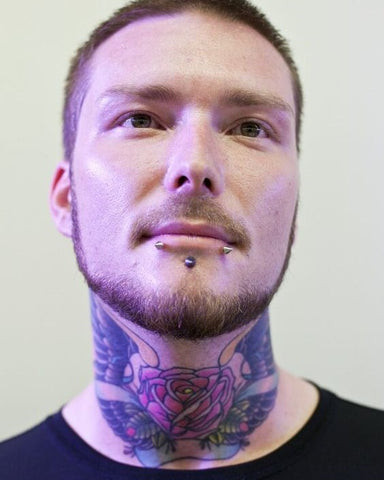 A man showcasing an intricate and artistic front neck tattoo design.