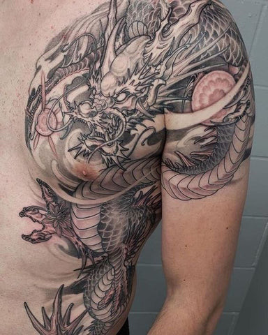 A skull and floral design tattoo on a man's front shoulder area