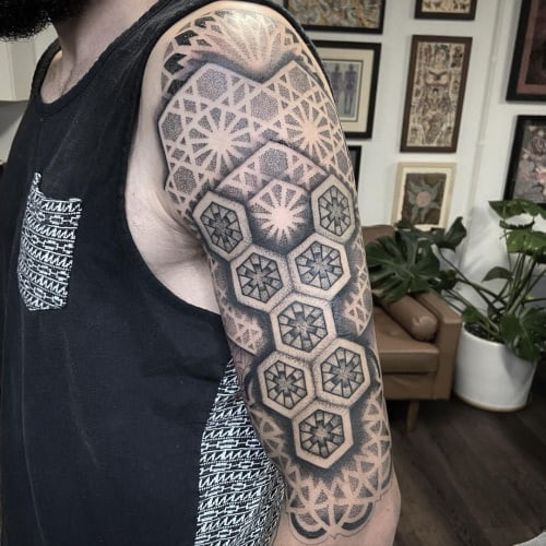 Geometric arm tattoo placed on the arm, typically the bicep or tricep area, featuring geometric designs as a classic and versatile choice.