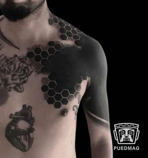 Geometric blackwork tattoo using solid black ink to create bold geometric shapes and patterns with high contrast.