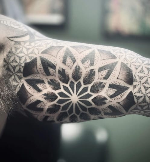 Intricate geometric blackwork tattoo design for men, demonstrating precise lines and patterns.