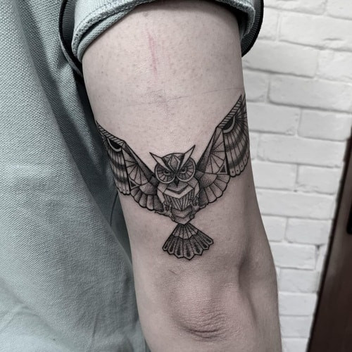 Geometric owl tattoo depicting an owl with geometric feathers and sharp lines, symbolizing wisdom and mystery.