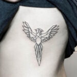 Geometric phoenix tattoo on side rib area, detailed black ink design.