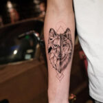 Geometric wolf tattoo crafted with precise lines and shapes to depict a wolf's head.