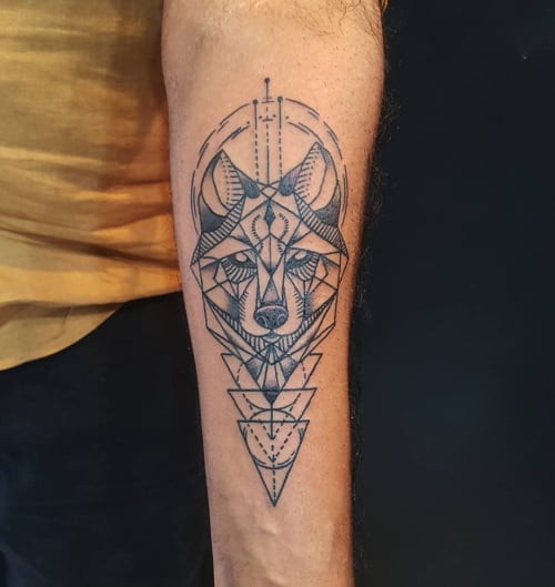 A symmetrical geometric wolf tattoo on a man's chest, using sharp lines and geometric shapes to create a balanced and modern design representing harmony.