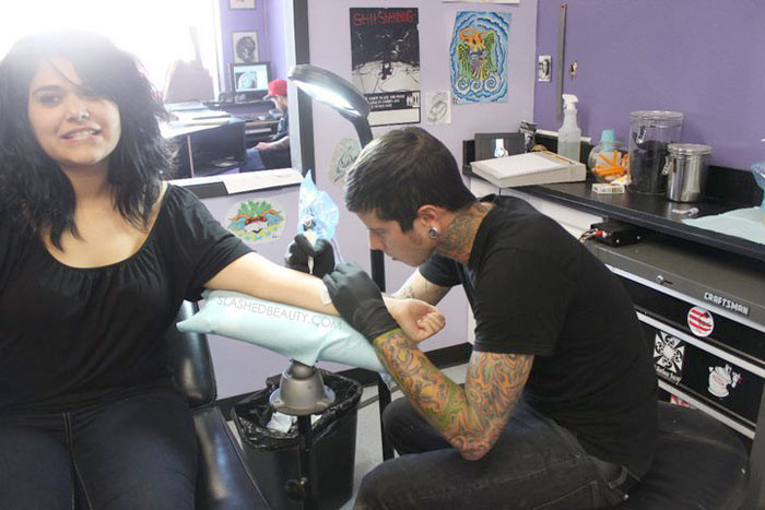 Artist Justin Coppolino tattooing a white ink design.