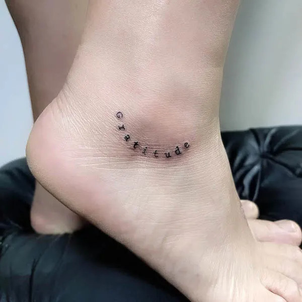 Gratitude one word ankle tattoo, an inspirational reminder to cherish small things and appreciate life's blessings