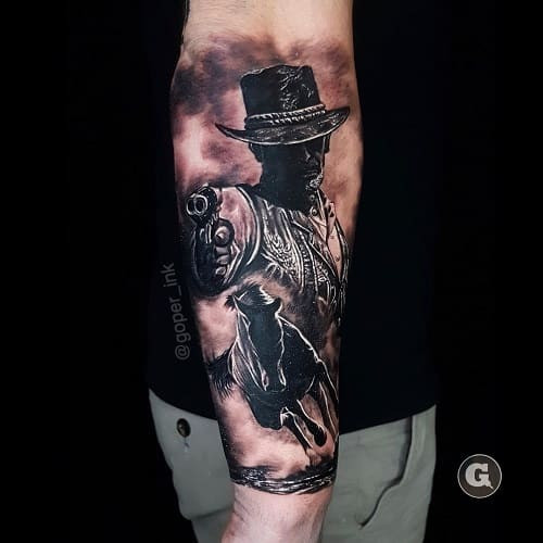 Gunslinger tattoo drawing a gun in black and grey