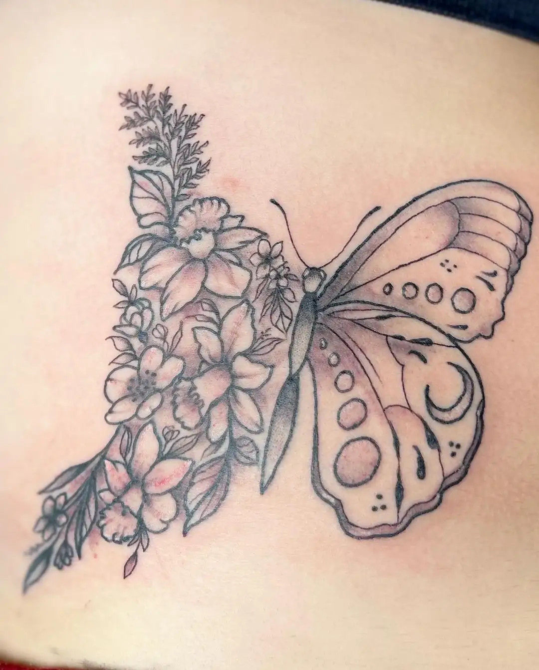 Creative half butterfly and half flower tattoo design on woman's ribs