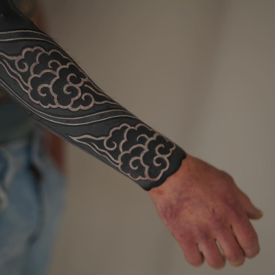 Close-up of a blackout tattoo with intricate white ink line-work detail