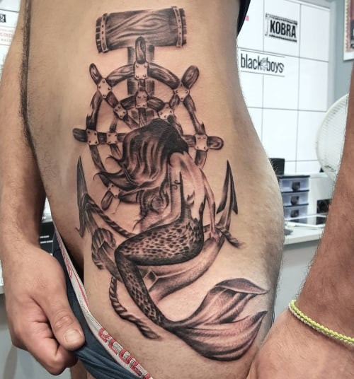 A hip tattoo extending to the thigh on a man's side, flowing and artistic