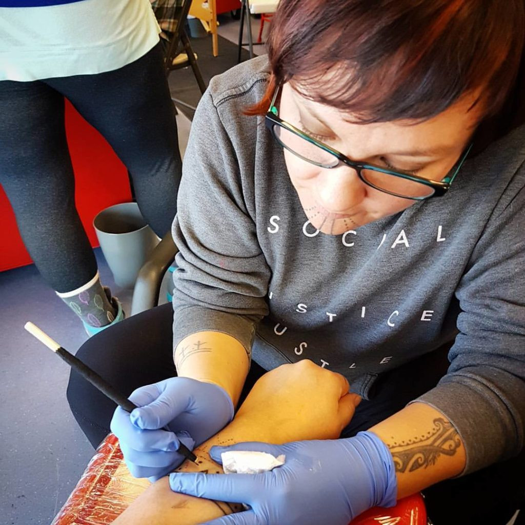 Holly Mititquq Nordlum tattoos a woman's arm, showcasing her dedication to reviving Inuit tattooing and sharing its cultural significance.