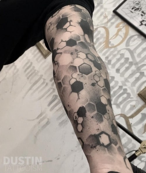 Geometric honeycomb tattoo on the arm, a modern and structured men tattoo idea.