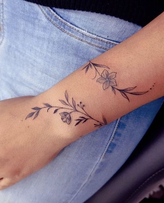 Feminine floral vine wrist tattoo wrapping around the arm, inspired by nature and grace