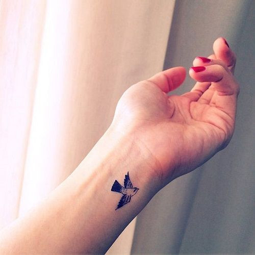 Tiny flying bird wrist tattoo for women