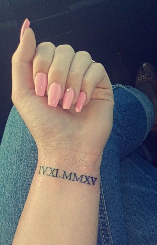 Classic Roman numerals wrist tattoo, marking significant dates or numbers with elegance for women