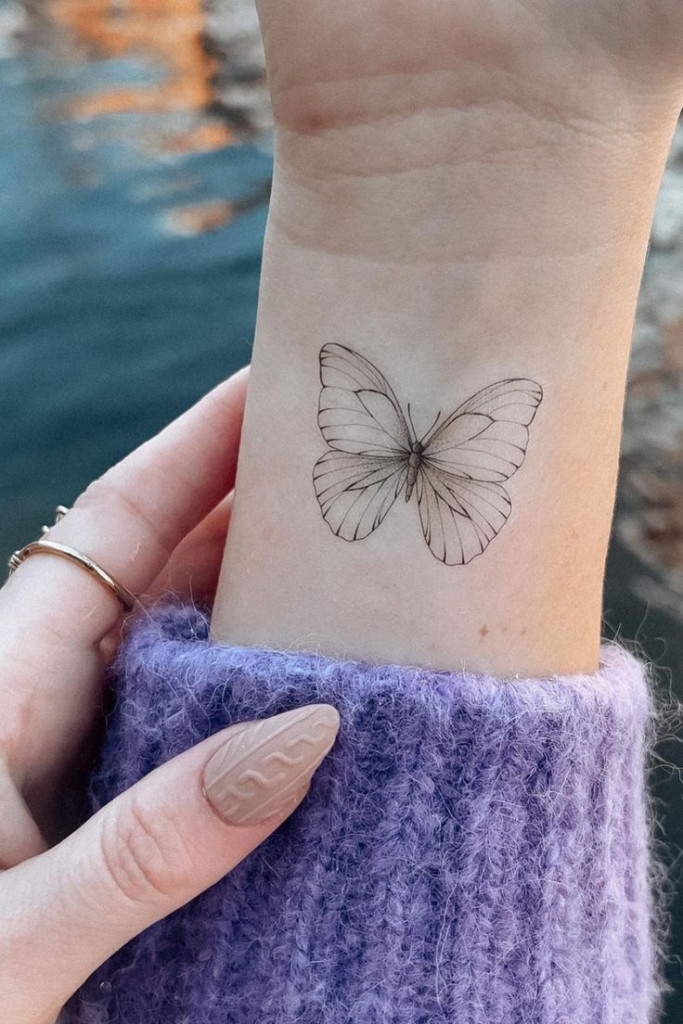 Subtle minimalist butterfly wrist tattoo, a chic and elegant design with simple lines for women