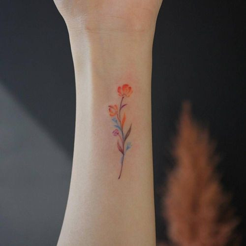 Artistic floral watercolor wrist tattoo, combining vibrant colors with delicate flower designs for women