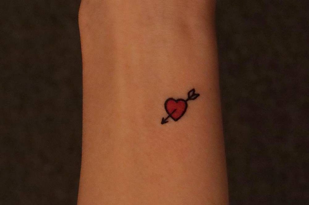 Romantic heart with arrow wrist tattoo, symbolizing love, passion, and Cupid's arrow for women