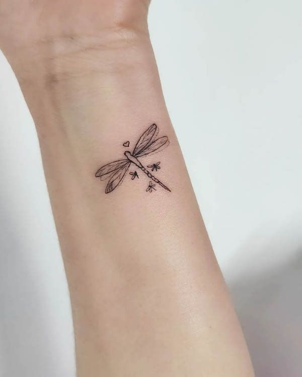 Tiny dragonfly outline wrist tattoo for women