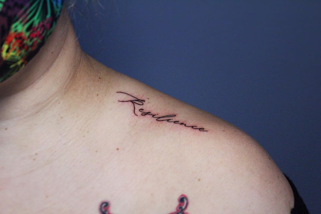 A phrase tattoo extending across the shoulder, conveying a personal message in a visually appealing way.