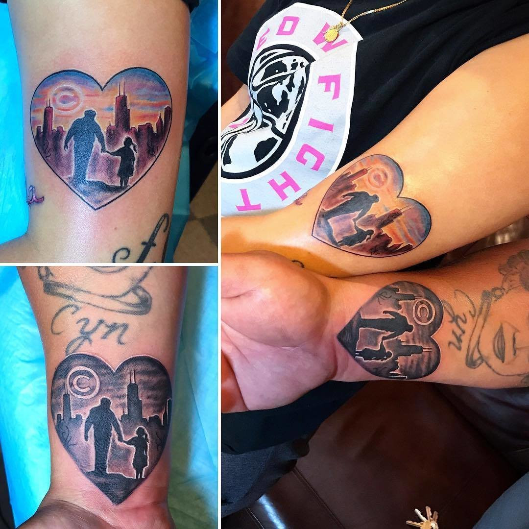 Father and daughter displaying forearm tattoos of hands holding within a heart shape, detailed with Chicago Cubs and skyline imagery, symbolizing shared roots and love for their city.