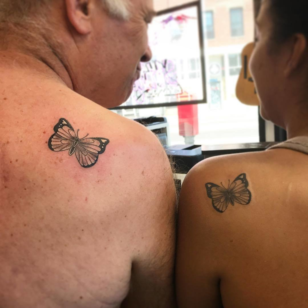 Father and daughter showcasing shoulder tattoos of butterfly designs, symbolizing transformation and shared journeys, commemorating a life milestone and road trip.