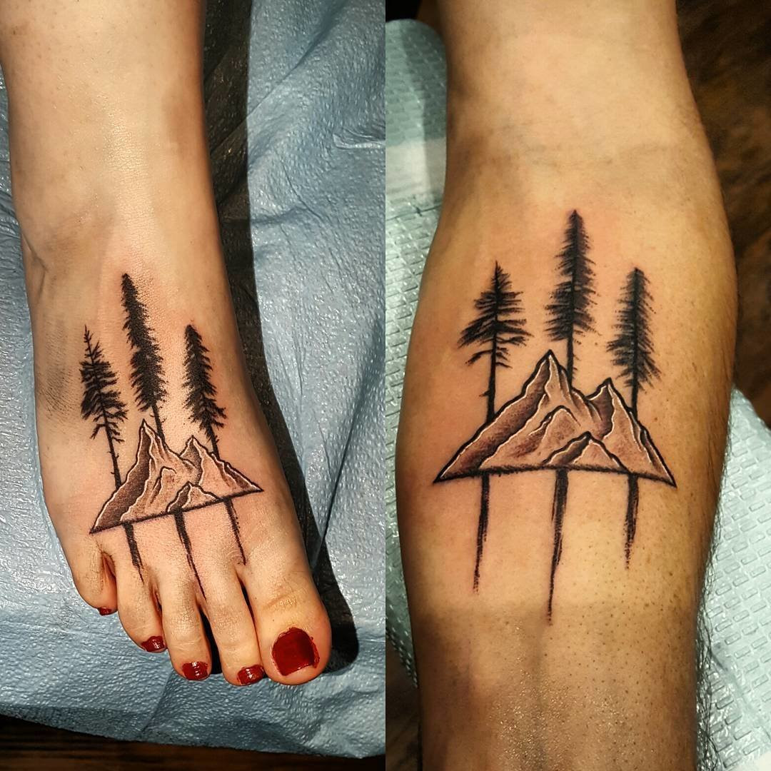 Father and daughter displaying forearm tattoos of mountain range designs with trees and roots, symbolizing shared adventures and the strong, grounded nature of their bond.