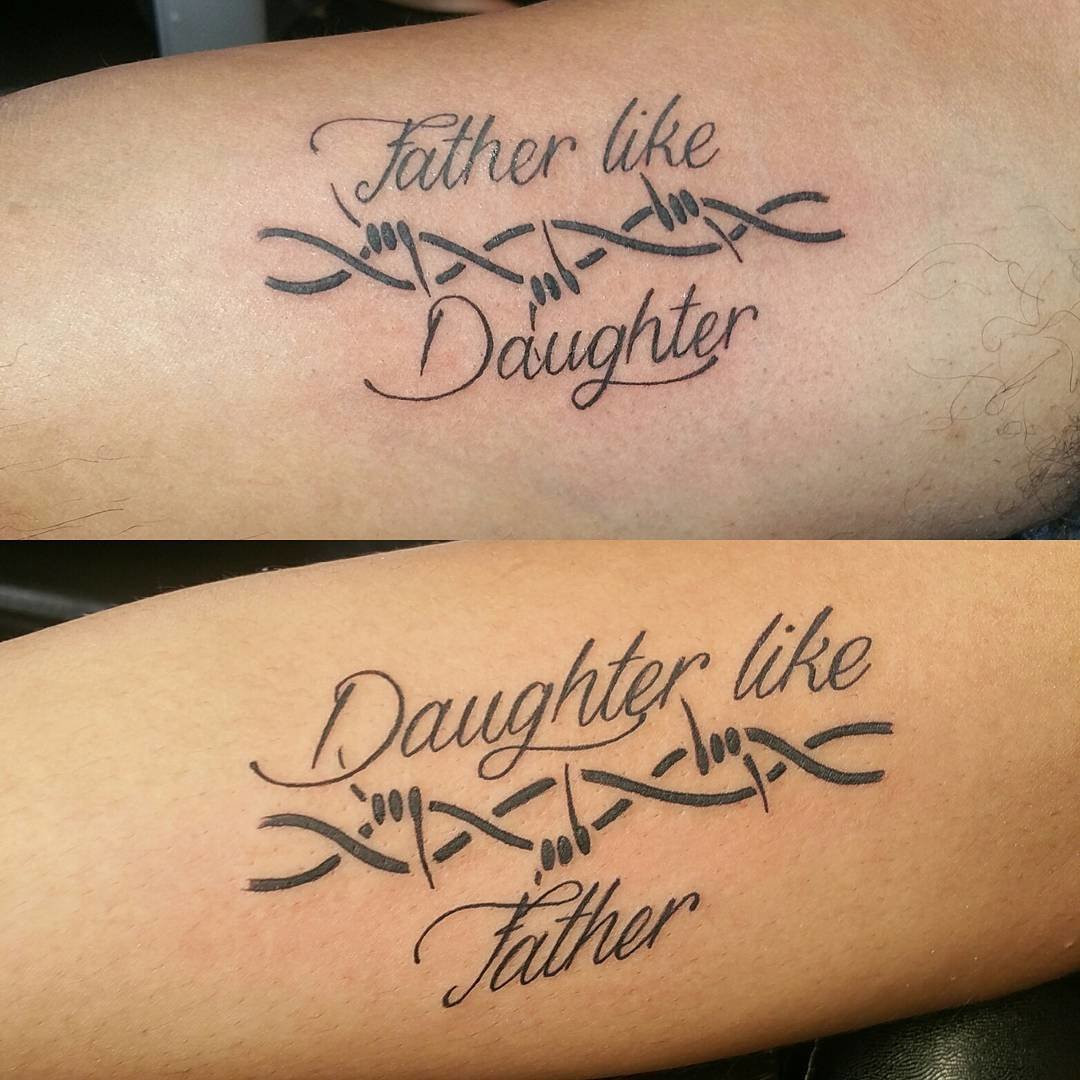 Father and daughter showcasing forearm tattoos of DNA strands interwoven with phrases &quot;Father like Daughter&quot; and &quot;Daughter like Father,&quot; symbolizing their genetic and familial connection.