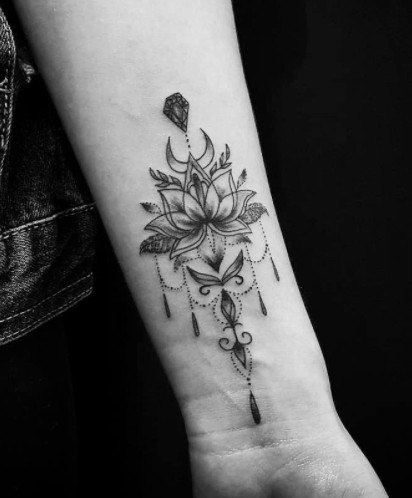 An ornamental mandala-inspired black ink tattoo with dotwork and shading on a wrist.