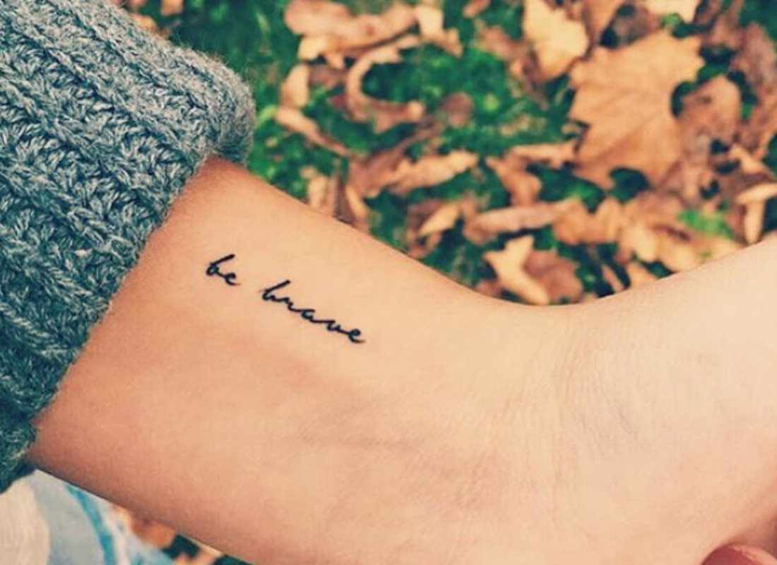 A wrist tattoo with the words &quot;be brave&quot; in a delicate script font.