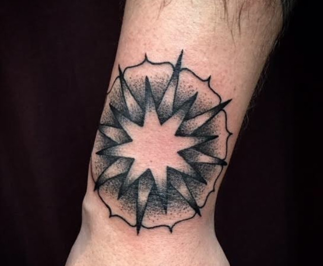 A black mandala tattoo with shading for depth on a wrist.