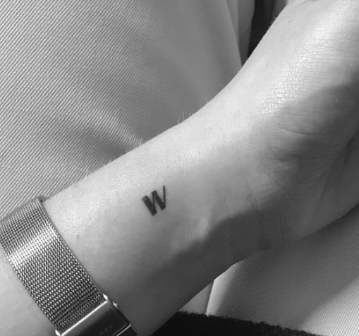 A tiny letter &quot;W&quot; tattoo on the side of a wrist.