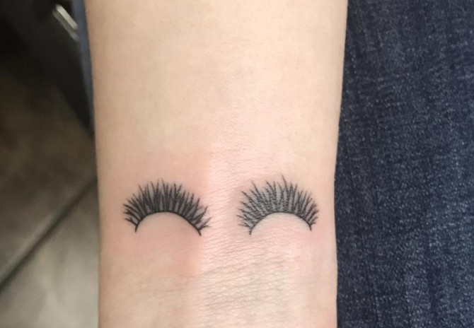 Cheeky eyelash tattoos on a wrist.