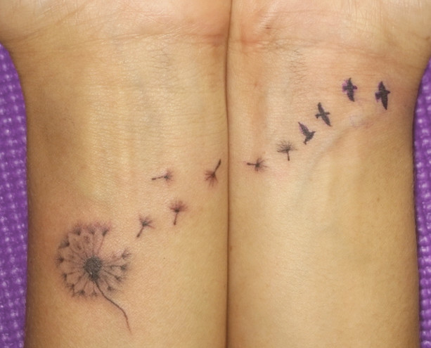 A dandelion turning into birds tattoo across two wrists.