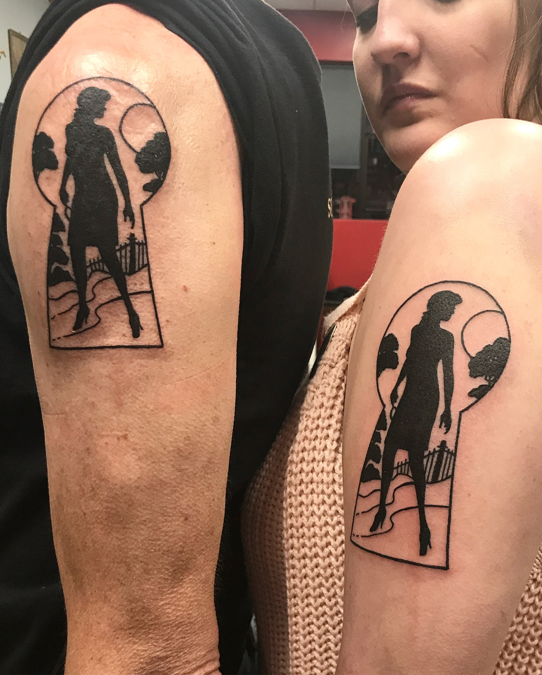 Father and daughter showing forearm tattoos inspired by Nancy Drew, featuring a stylized book and magnifying glass representing shared interests.