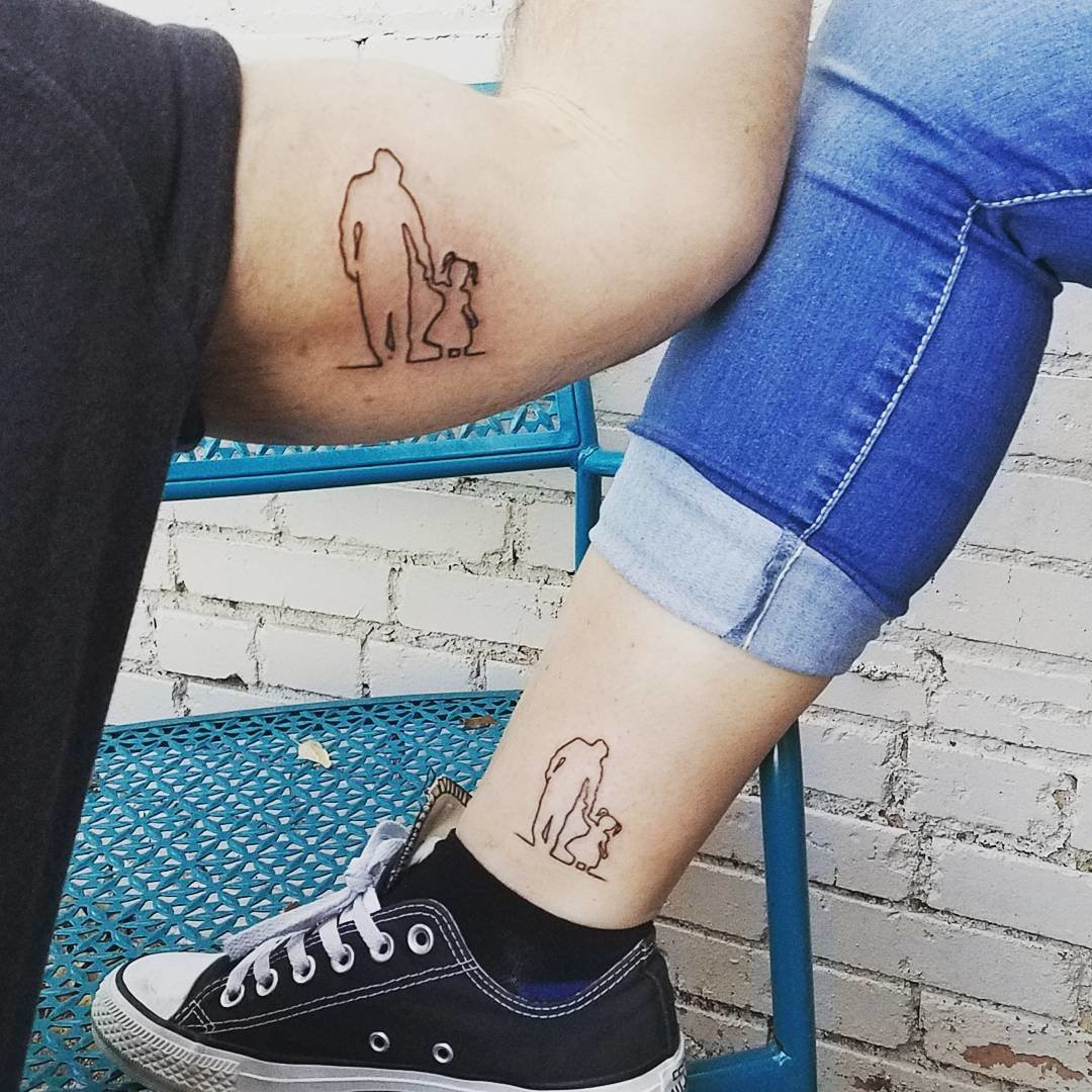 Father and daughter showcasing forearm tattoos featuring a minimalist outline of a father holding a child's hand, a sweet and simple representation of their bond.