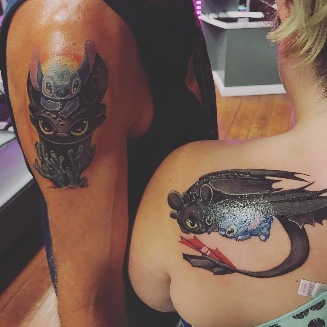 Father and daughter displaying ankle tattoos featuring Disney characters Stitch and Toothless merged into one design, a unique and whimsical choice.